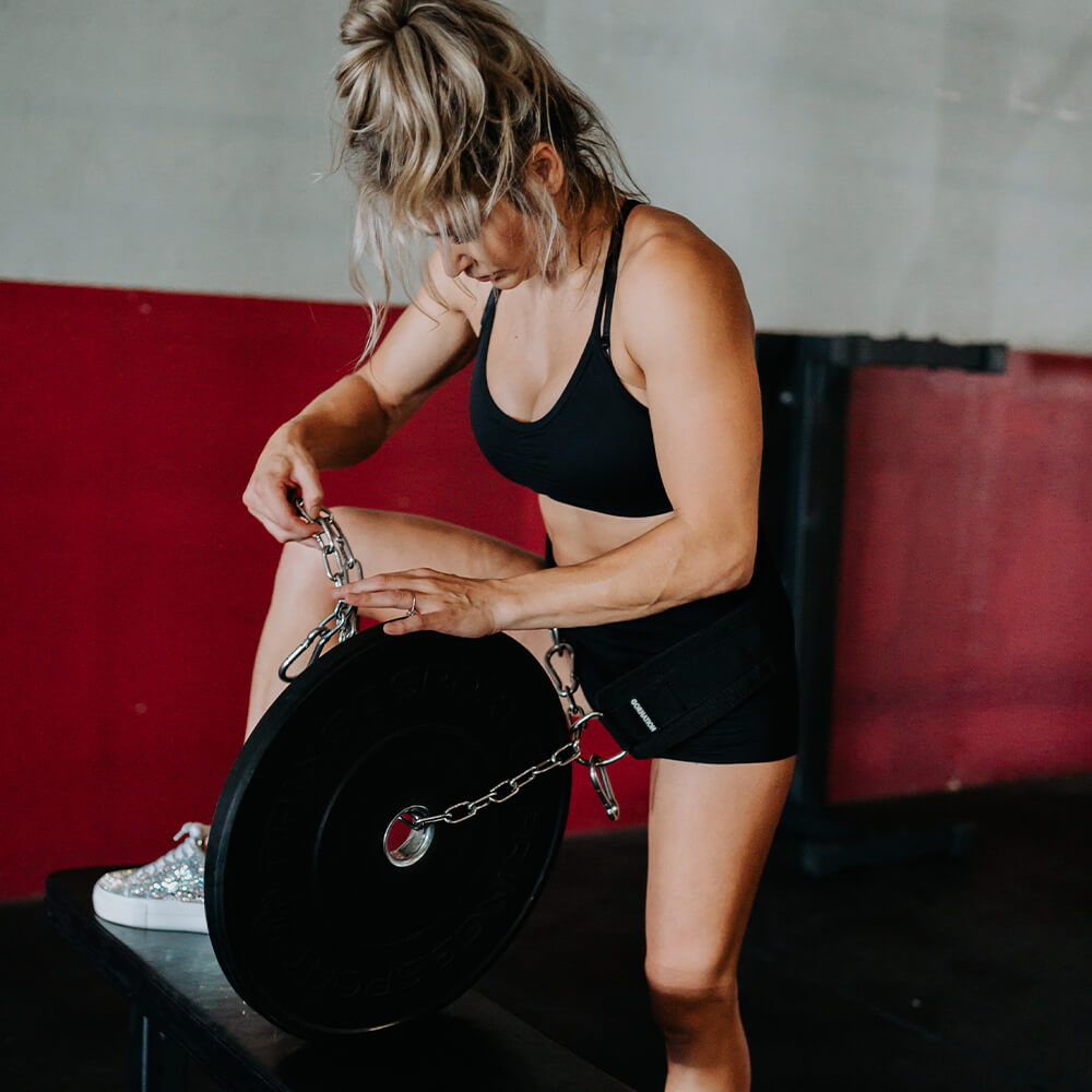 female calisthenics athlete adding weight on dip belt for weighted calisthenics