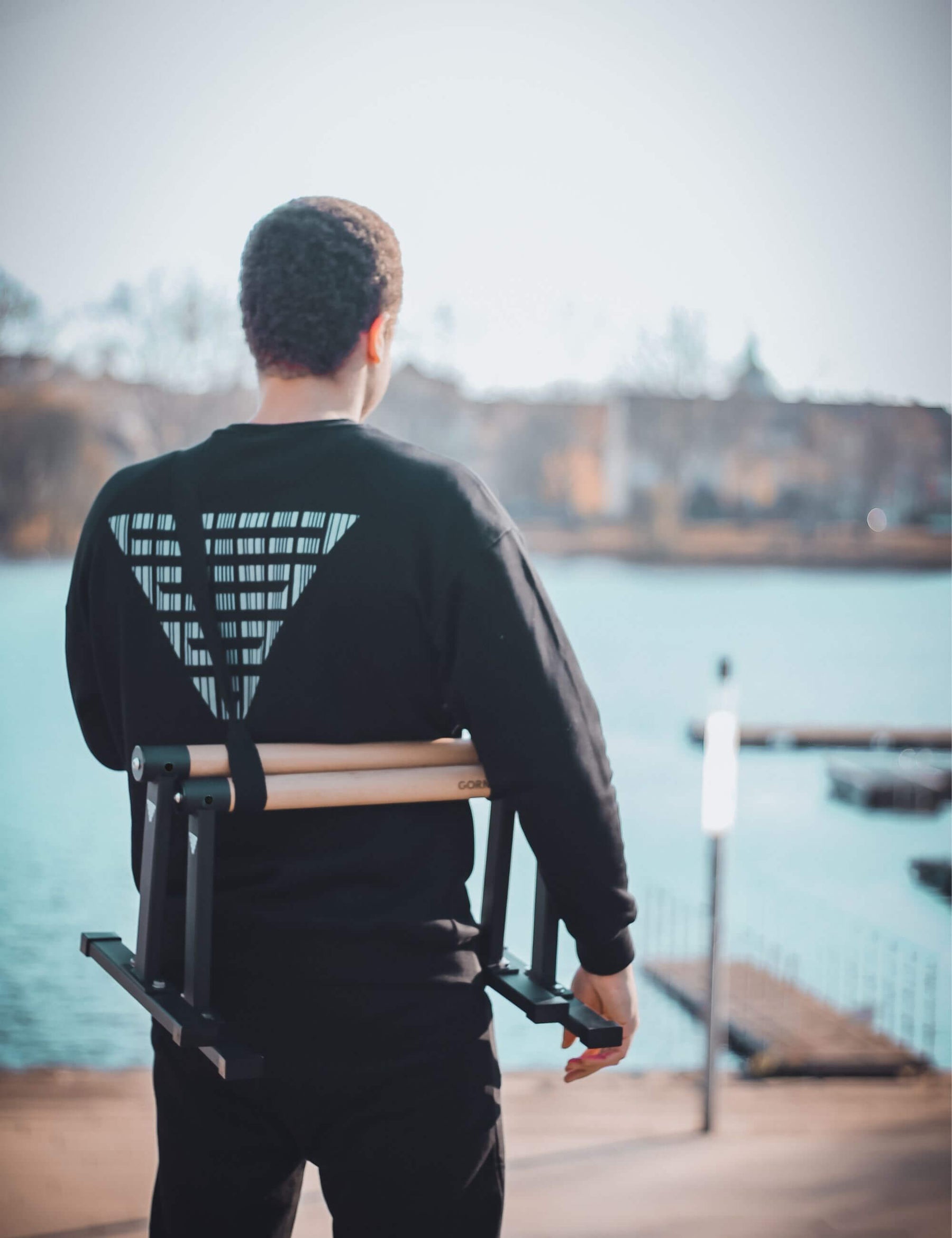 Calisthenics athlete wearing the Max paralettes and the Gornation barcode sweater at the water.