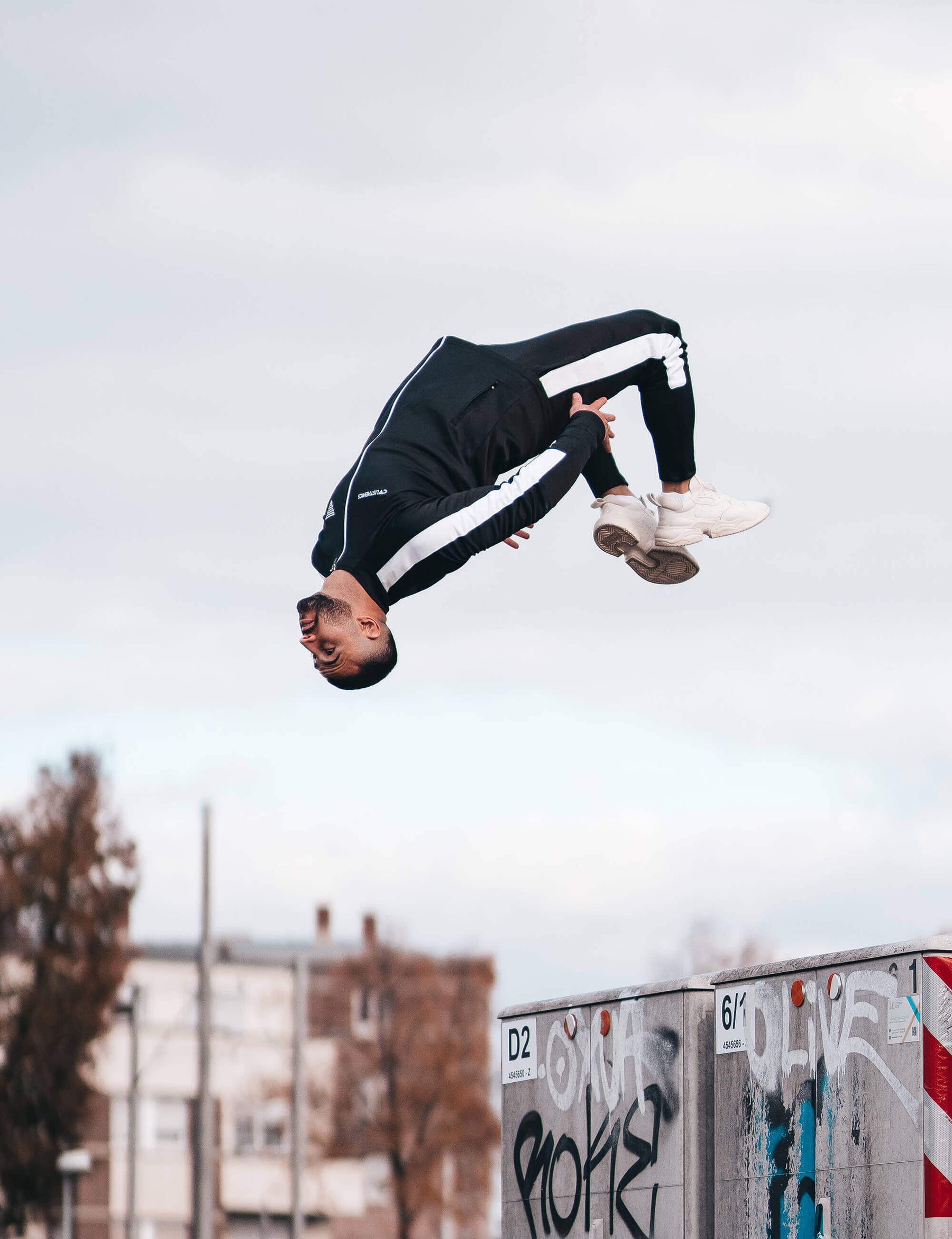 calisthenics athlete doing a backflip in black/white calisthenics jacket