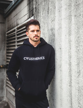 Calisthenics athlete wearing calisthenics hoodie and skinny sweatpant with a concrete background.