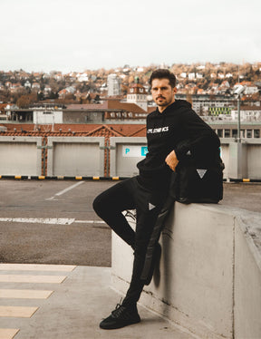 streetworkout athlete wearing perfomance sweatpants Calisthenics hoodie and Gornation Bakpack in a urban area.