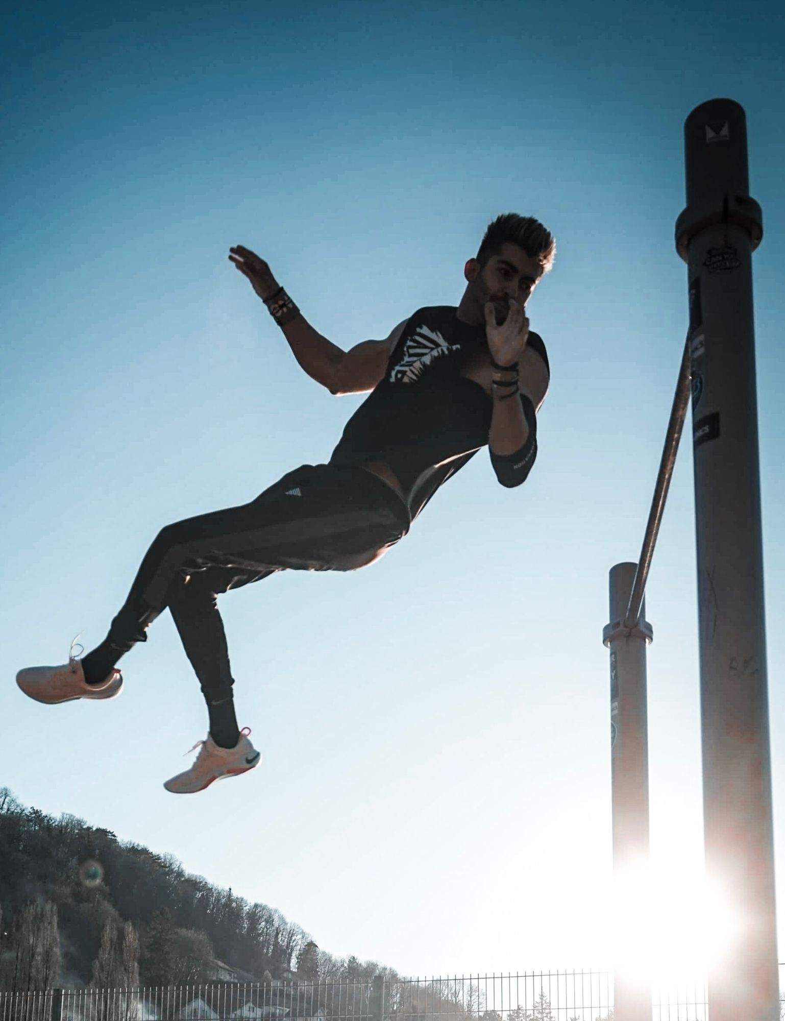 Calisthenics Athlete GAEL performing Dynamics move on pullup bar with vintage black tank top for men.