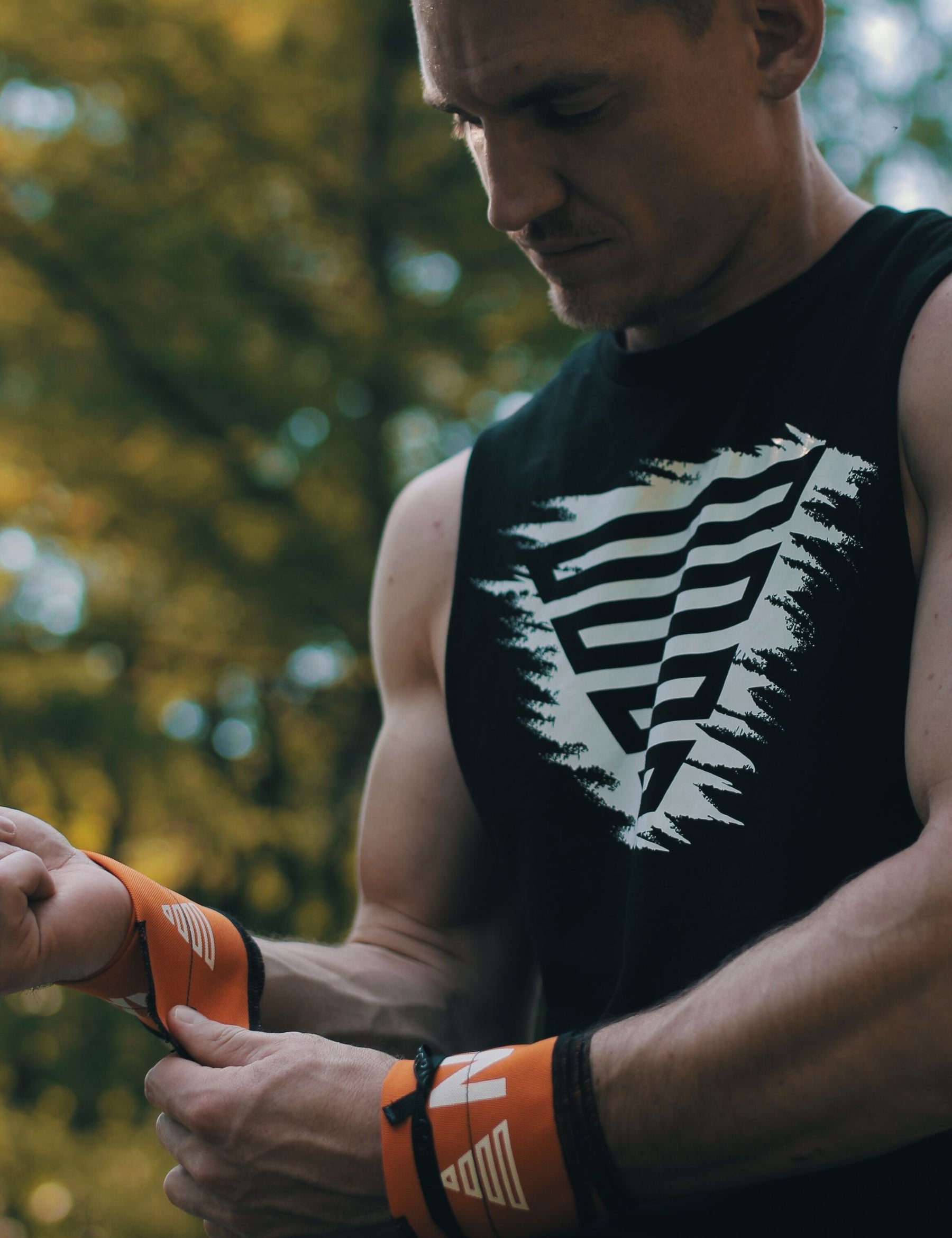 Black vintage tank top with orange gornation performance wrist wraps in forrest.