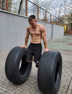 Street Workout & Calisthenics Athlet World Record Holder in Muscle Ups trägt die GORNATION Heavy Shorts Men Black und macht Dips auf Reifen
